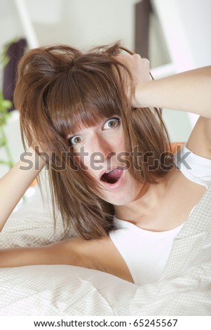 bed clock alarm - surprised woman in bed holding her head with both hands
