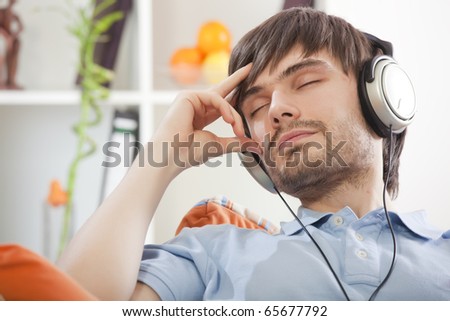 young man with closed eyes and earphones hearing music