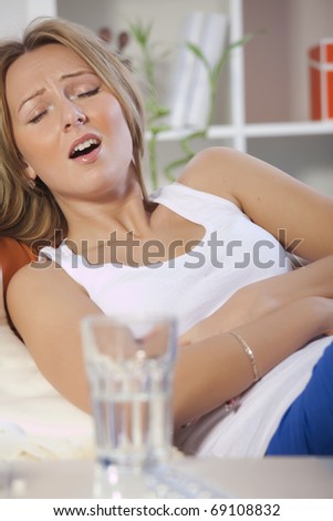 young woman holding her stomach in pain with both hands