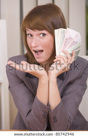 happy business woman with stack of money in office