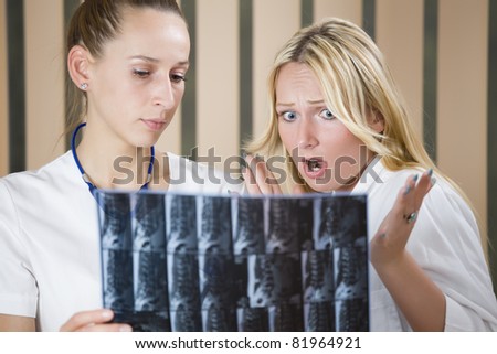 two women doctors reading MRI film scans of patient\'s spine - shocked diagnosis scene.