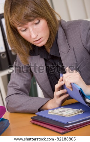 young surprised woman looking at money hidden between files