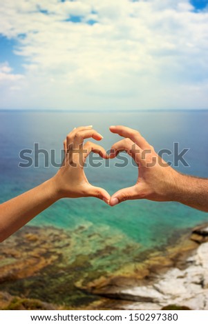 couple hands in the heart sign, love and the sea