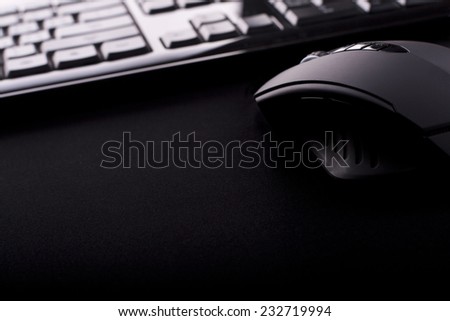 Black gaming mouse with keyboard on black mouse mat