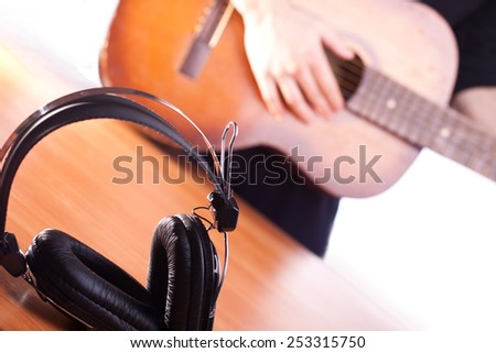 playing acoustic guitar on background and black headphones on a front