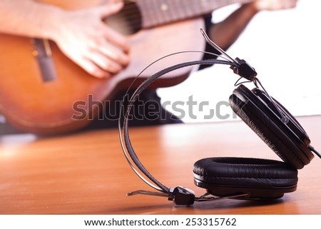 acoustic guitar on background and big black headphones in focus