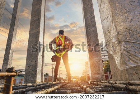 Construction worker wearing safety work at high uniform on scaffolding at construction site on during sunset,Working at height equipment. Foto stock © 