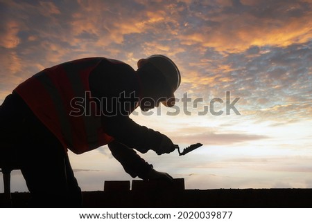 Silhouette construction mason worker bricklayer, construction worker laying bricks and building barbecue in industrial site.