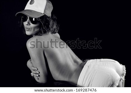 Sexy topless woman in a cap and shorts