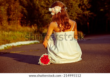 Beautiful girl with flowers in the summer landscape