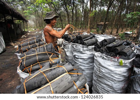 NAKHON SI THAMMARAT, THAILAND - MAY 12 : Unidentified worker in a charcoal factory packs charcoals into plastic bags for shipment on May 12, 2010 in Nakhon Si Thammarat, Thailand.