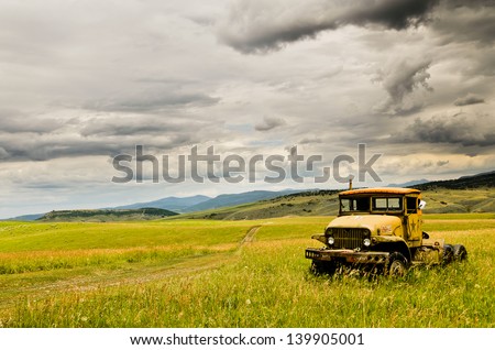 Old Rusty Truck in Middle of Field and Stormy Clouds