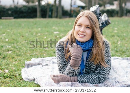 Portrait of a young woman lying on a blanket in a park