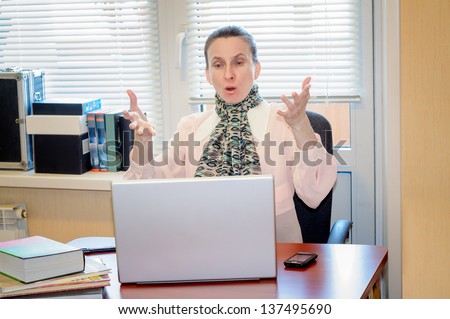 A fifty years old woman working in office with a laptop computer is very angry with the modern technology
