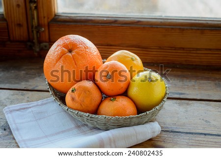 Orange, tangerines and lemon in a silver filigree basket with a table napkin