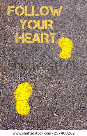 Yellow footsteps on sidewalk towards Follow your heart message.Conceptual image