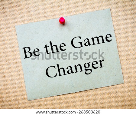 BE THE GAME CHANGER Message. Recycled paper note pinned on cork board. Concept Image