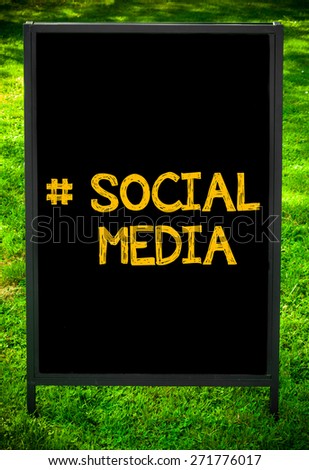 Hashtag Social Media message on sidewalk blackboard sign against green grass background. Copy Space available. Concept image