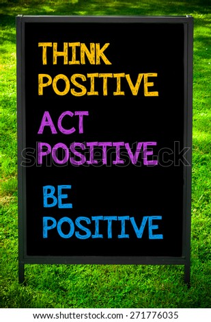 THINK ACT BE POSITIVE  message on sidewalk blackboard sign against green grass background. Copy Space available. Concept image