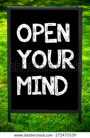 OPEN YOUR MIND  message on sidewalk blackboard sign against green grass background. Copy Space available. Concept image