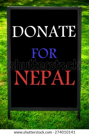 DONATE FOR NEPAL  message on sidewalk blackboard sign against green grass background. Concept image