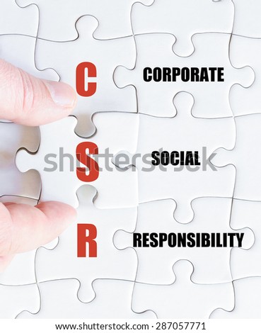 Hand of a business man completing the puzzle with the last missing piece.Concept image of Business Acronym CSR as Corporate Social Responsibility