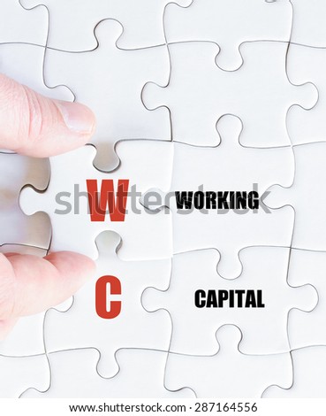 Hand of a business man completing the puzzle with the last missing piece.Concept image of Business Acronym WC as Working Capital