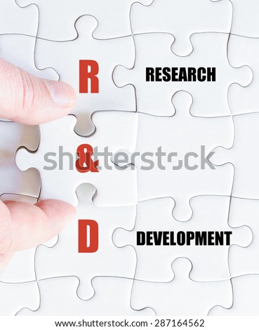 Hand of a business man completing the puzzle with the last missing piece.Concept image of Business Acronym R&D as Research and Development