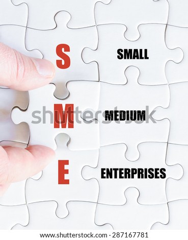 Hand of a business man completing the puzzle with the last missing piece.Concept image of Business Acronym SME as Small Medium Enterprises