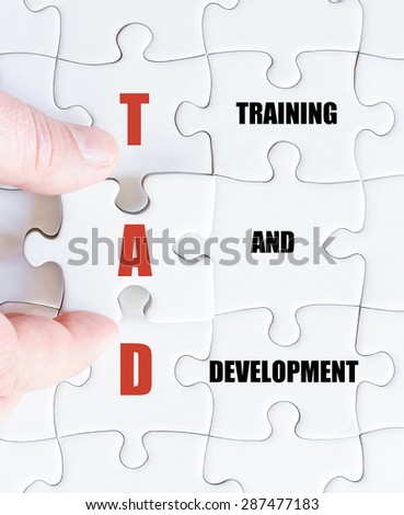 Hand of a business man completing the puzzle with the last missing piece.Concept image of Business Acronym TAD as Training And Development