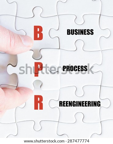 Hand of a business man completing the puzzle with the last missing piece.Concept image of Business Acronym BPR as Business Process Reengineering