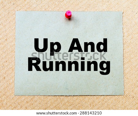 Up And Running  written on paper note pinned with red thumbtack on wooden board. Business conceptual Image