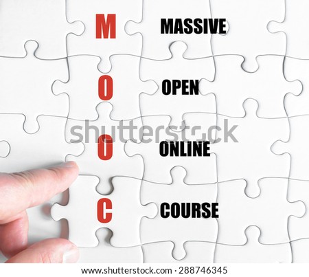 Hand of a business man completing the puzzle with the last missing piece.Concept image of Business Acronym MOOC as Massive Open Online Course