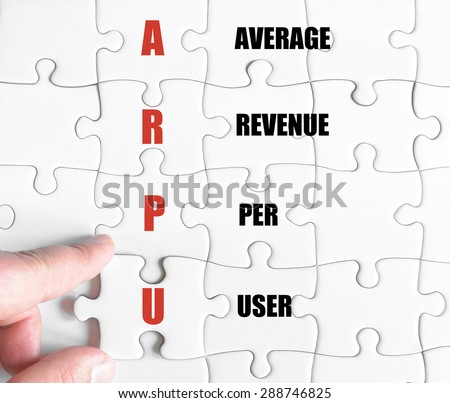 Hand of a business man completing the puzzle with the last missing piece.Concept image of Business Acronym ARPU as Average Revenue Per User