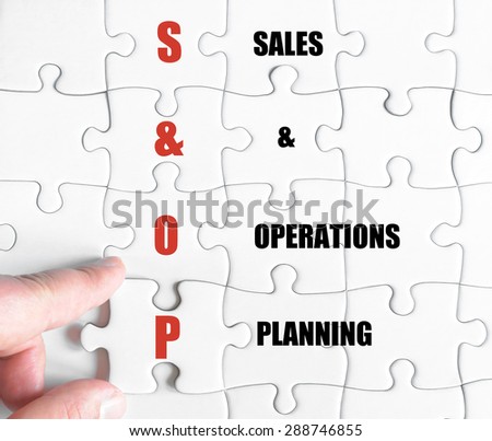 Hand of a business man completing the puzzle with the last missing piece.Concept image of Business Acronym SOP as Sales And Operations Planning
