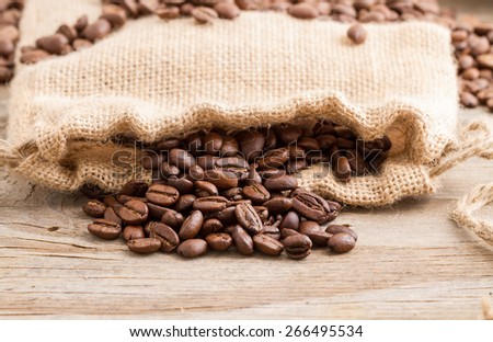 Coffee beans in a coffee bag on wooden background