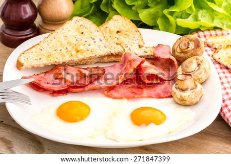 Full English breakfast with bacon, fried eggs, mushrooms and toasts