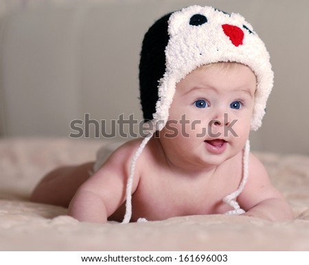happy newborn baby in a hat with an penguin