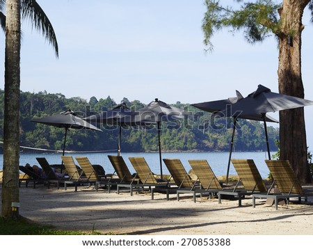 Summer, Travel, Vacation and Holiday concept - Beach chairs and umbrella on wooden desk against blue sky in Moo Koh Surin,Thailand