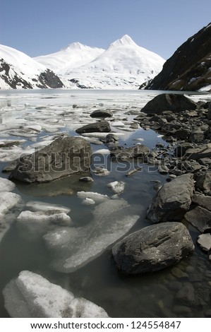 Stones, ice and snow capped mountains near alaskan Portage glacier