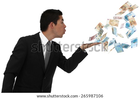 Businessman blowing money out of his hand throwing it away or waisting it.