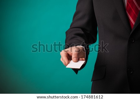Business man showing a blank empty business card over green background