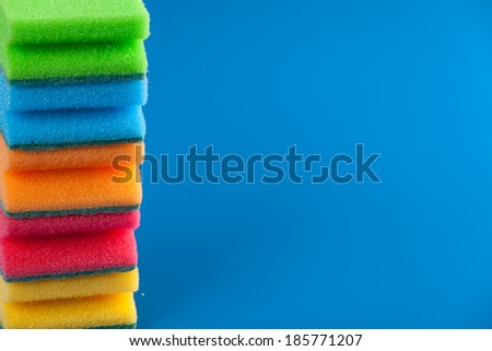 Pile of colorful sponge scourer over blue background. Copy space for text.