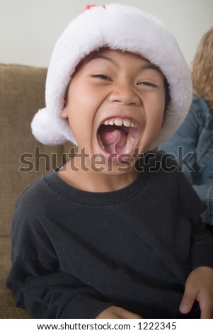 Happy boy in santa hat with mouth wide open showing inside of mouth