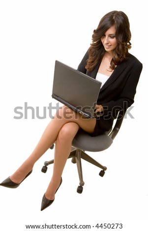 Attractive brunette business woman sitting on a chair wearing black business suit while typing on a laptop computer