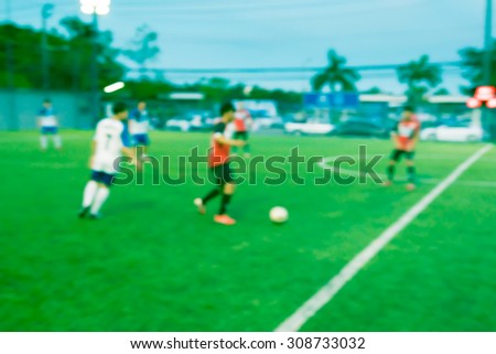 Blur of young boy playing a youth soccer match outdoors on an green soccer pitch.