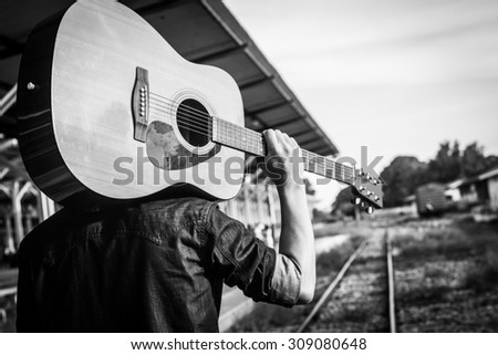 Guy with guitar on the railway road.Black and white photo
