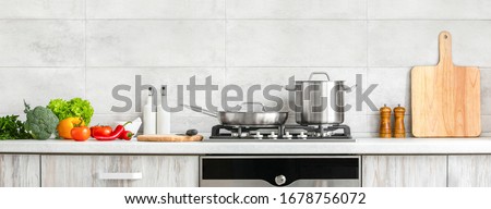 Fresh clean vegetables being put on a kitchen desk top, ready for cooking, front view of modern kitchen countertop with domestic culinary utensils on it, home healthy cooking concept banner