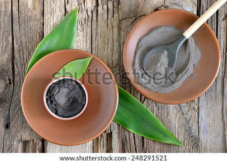 Cosmetic clay in a ceramic bowl decorated with fresh green leaves. Spa body and face treatment