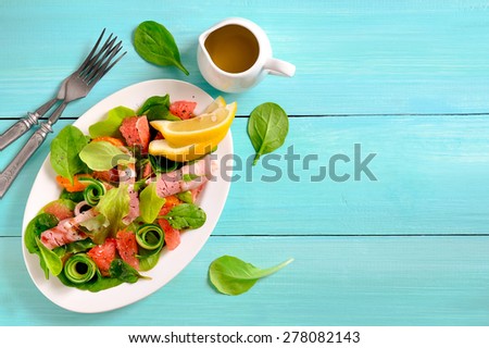 Fresh juicy summer salad with slices of grapefruit and deli ham seasoned with spinach and lettuce leaves and balsamic vinegar, top view